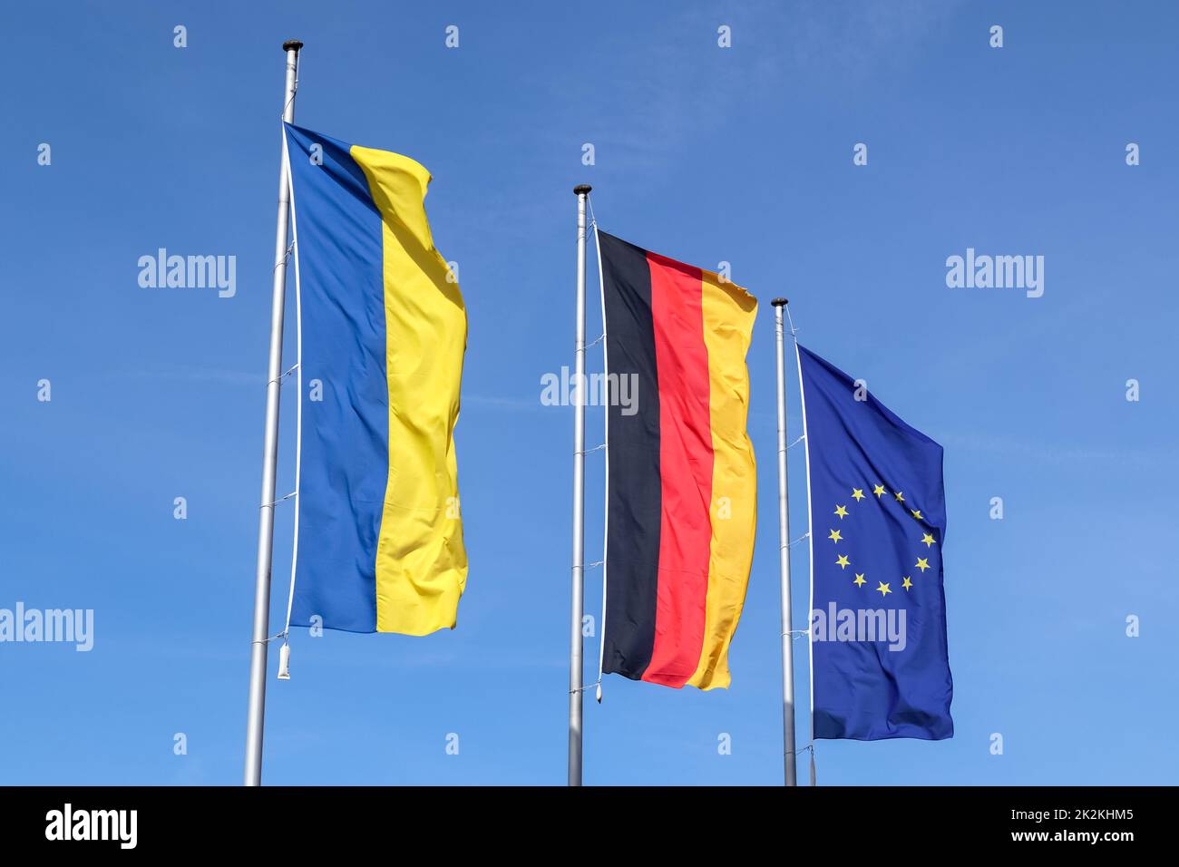 Le bandiere di Ucraina, Germania e Unione europea volano fianco a fianco contro il cielo blu. Foto Stock