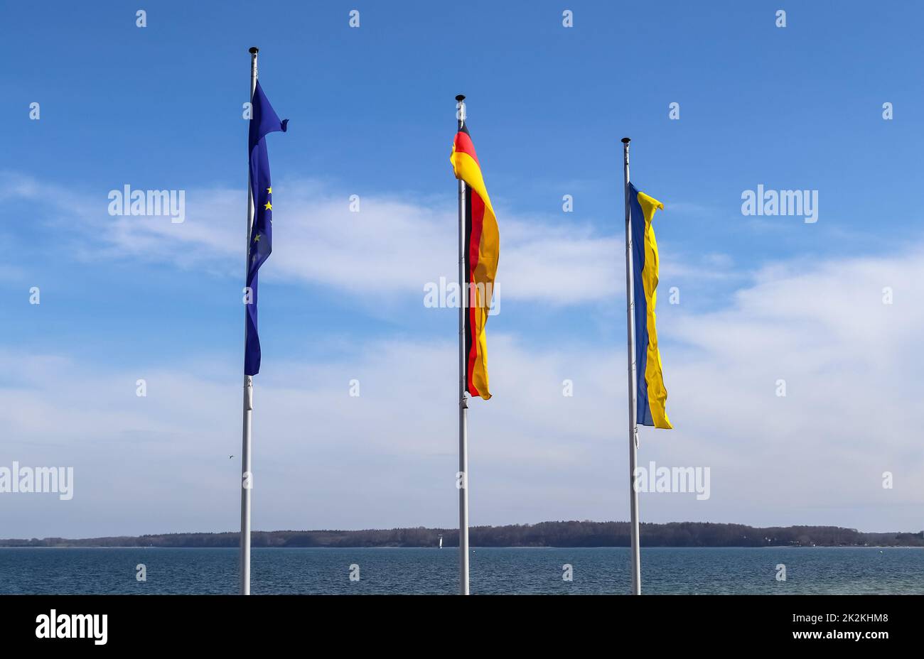 Le bandiere di Ucraina, Germania e Unione europea volano fianco a fianco contro il cielo blu. Foto Stock