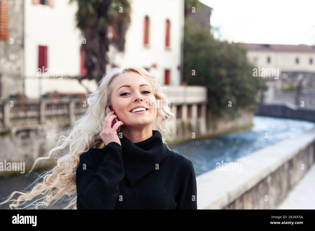 Felice giovane donna che lancia i suoi lunghi capelli biondi Foto Stock