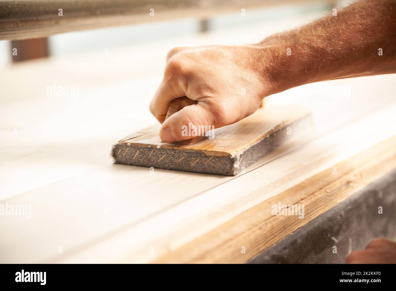 Uomo non identificabile che leviga un grande pezzo di legno Foto Stock