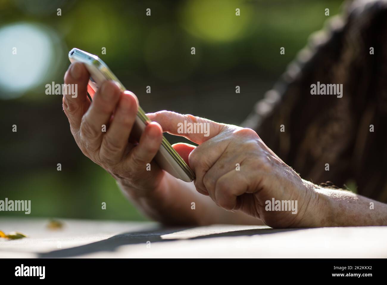 un dito della mano invecchiata che tocca un telefono cellulare Foto Stock