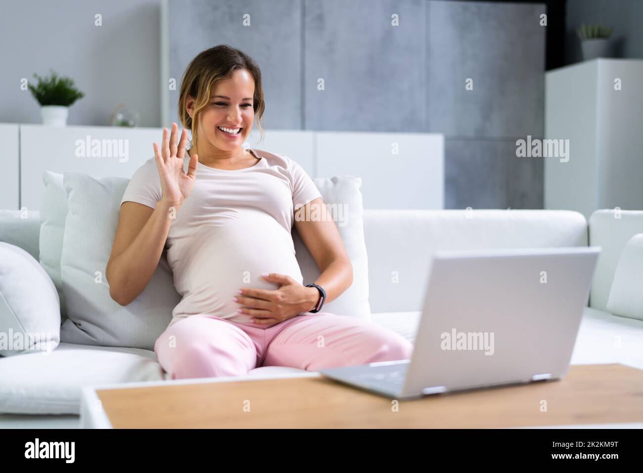 Donna incinta che usa la videochiamata in linea con medico sul laptop Foto Stock