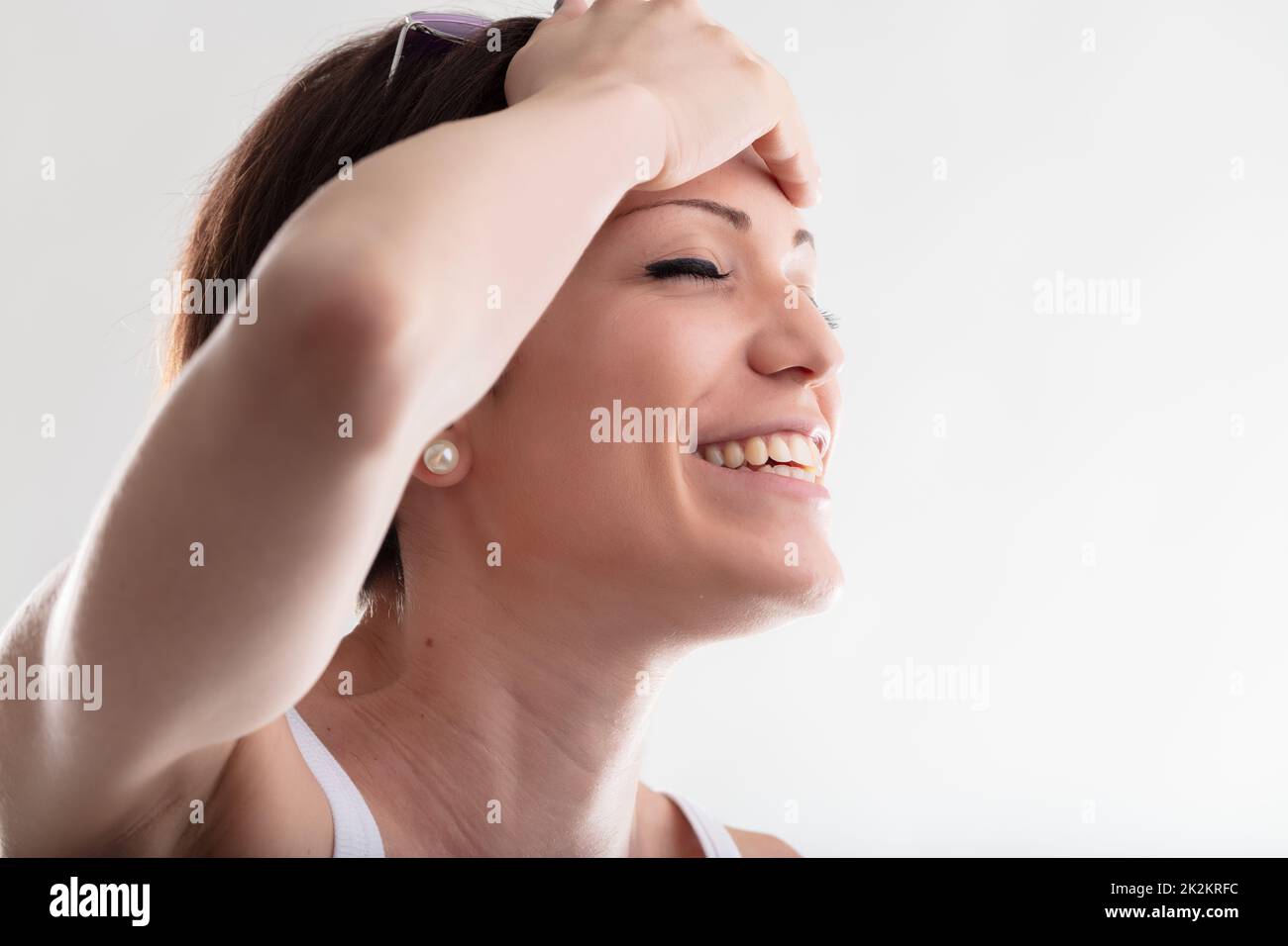 Felice giovane donna sorridente che tiene la mano alla fronte Foto Stock