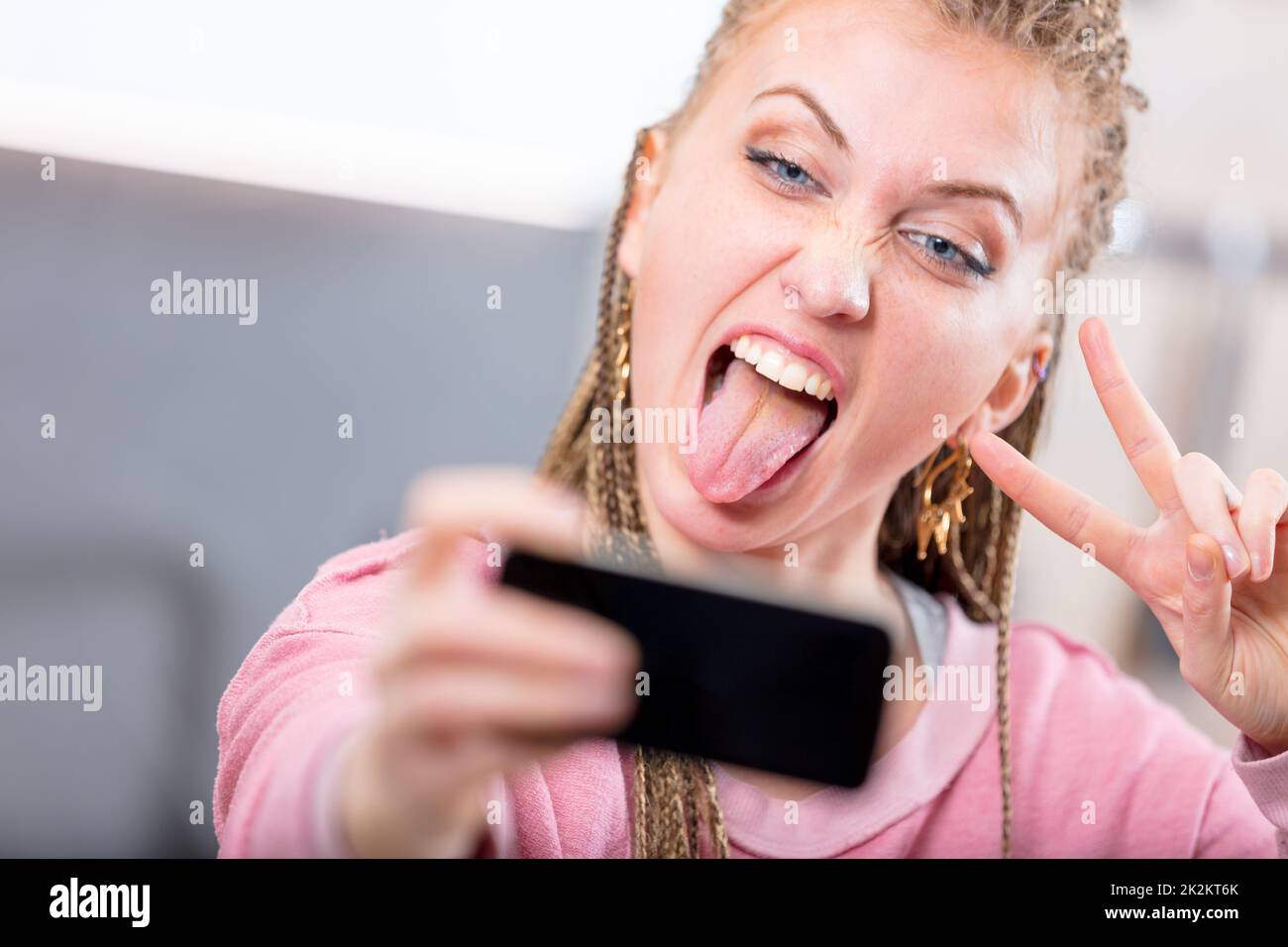 Giovane donna che tira una faccia goofy per un selfie Foto Stock