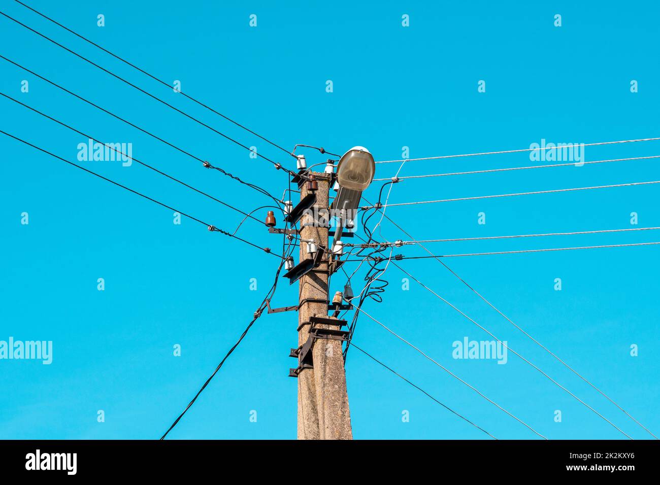 Fili elettrici appesi su un palo con una lampada di illuminazione Foto Stock