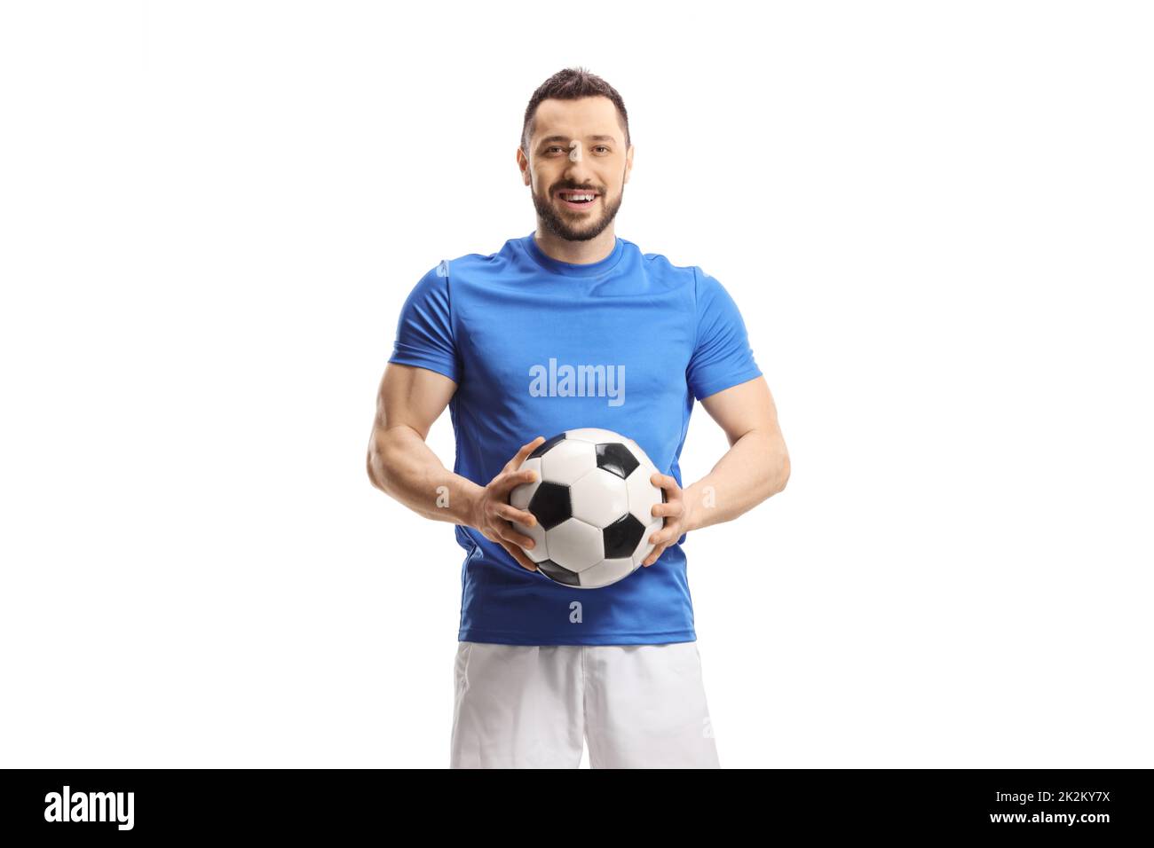 Giocatore di calcio che tiene una palla e guarda la telecamera isolata su sfondo bianco Foto Stock