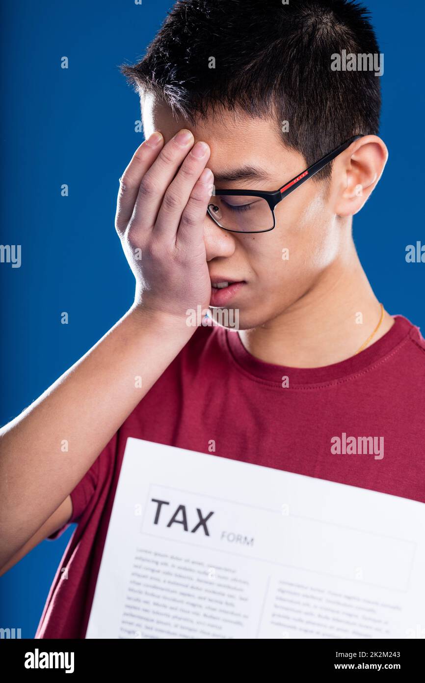 uomo asiatico preoccupato da una forma fiscale Foto Stock
