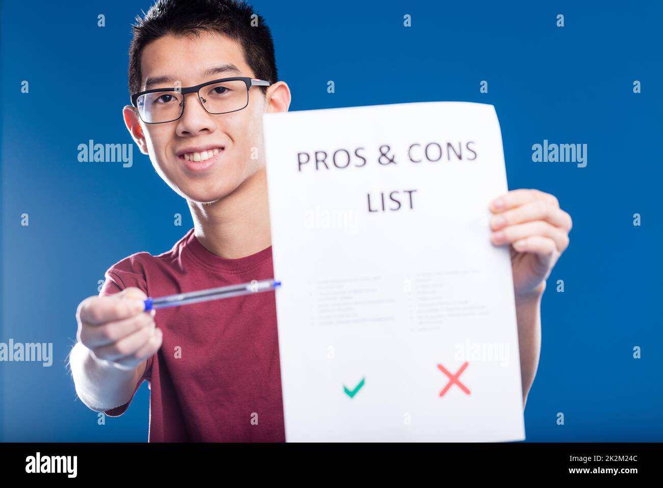 ragazzo asiatico felice mostrando una lista di pro e contro Foto Stock