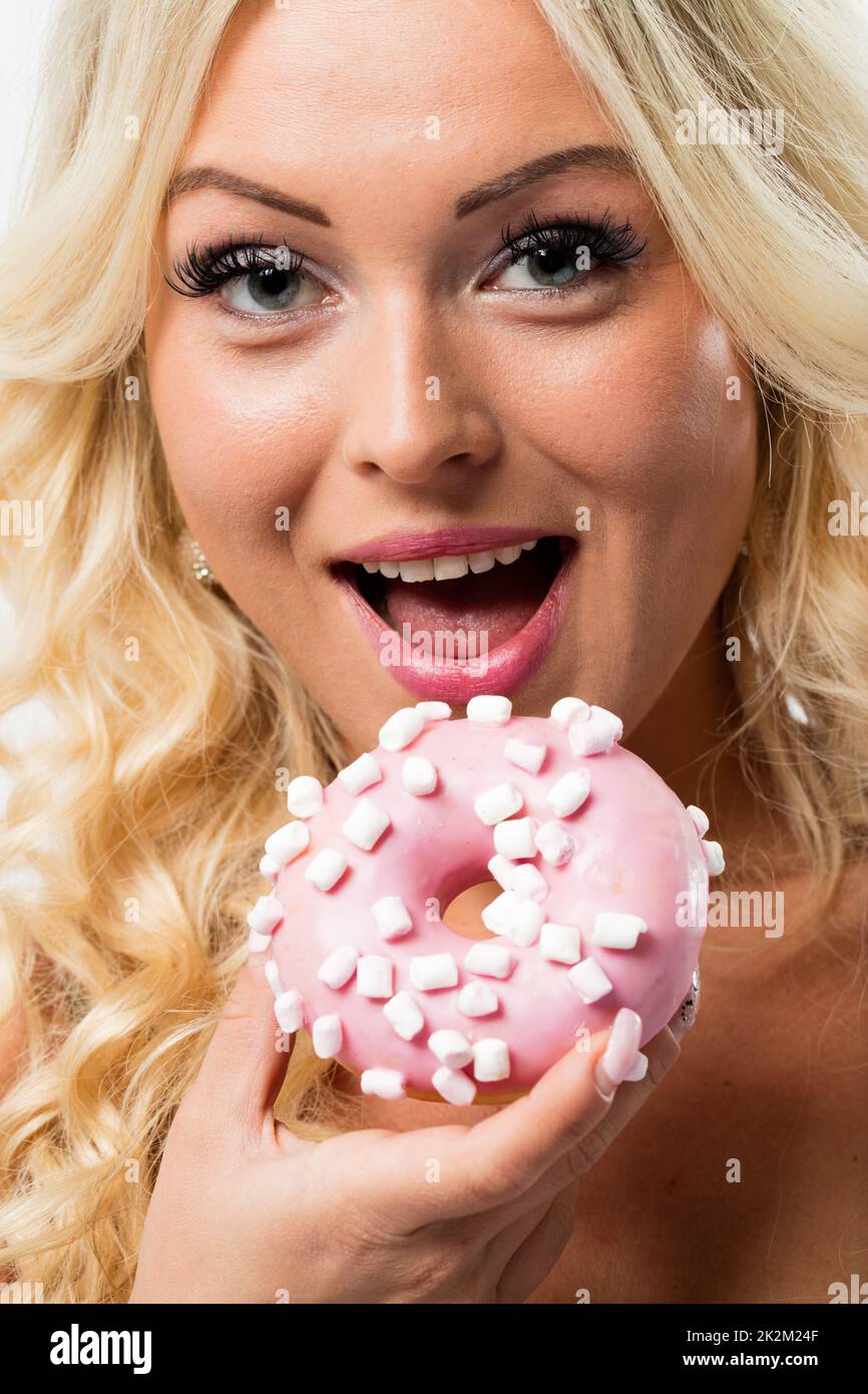 donna felice di mangiare una ciambella rosa Foto Stock
