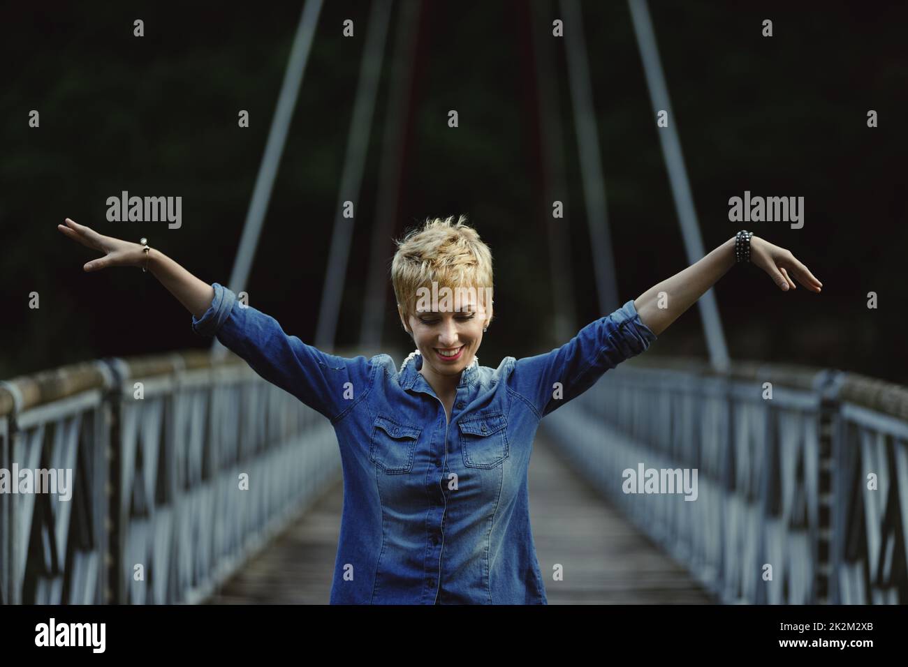 ritratto di giovane donna su ponte e braccia distese Foto Stock