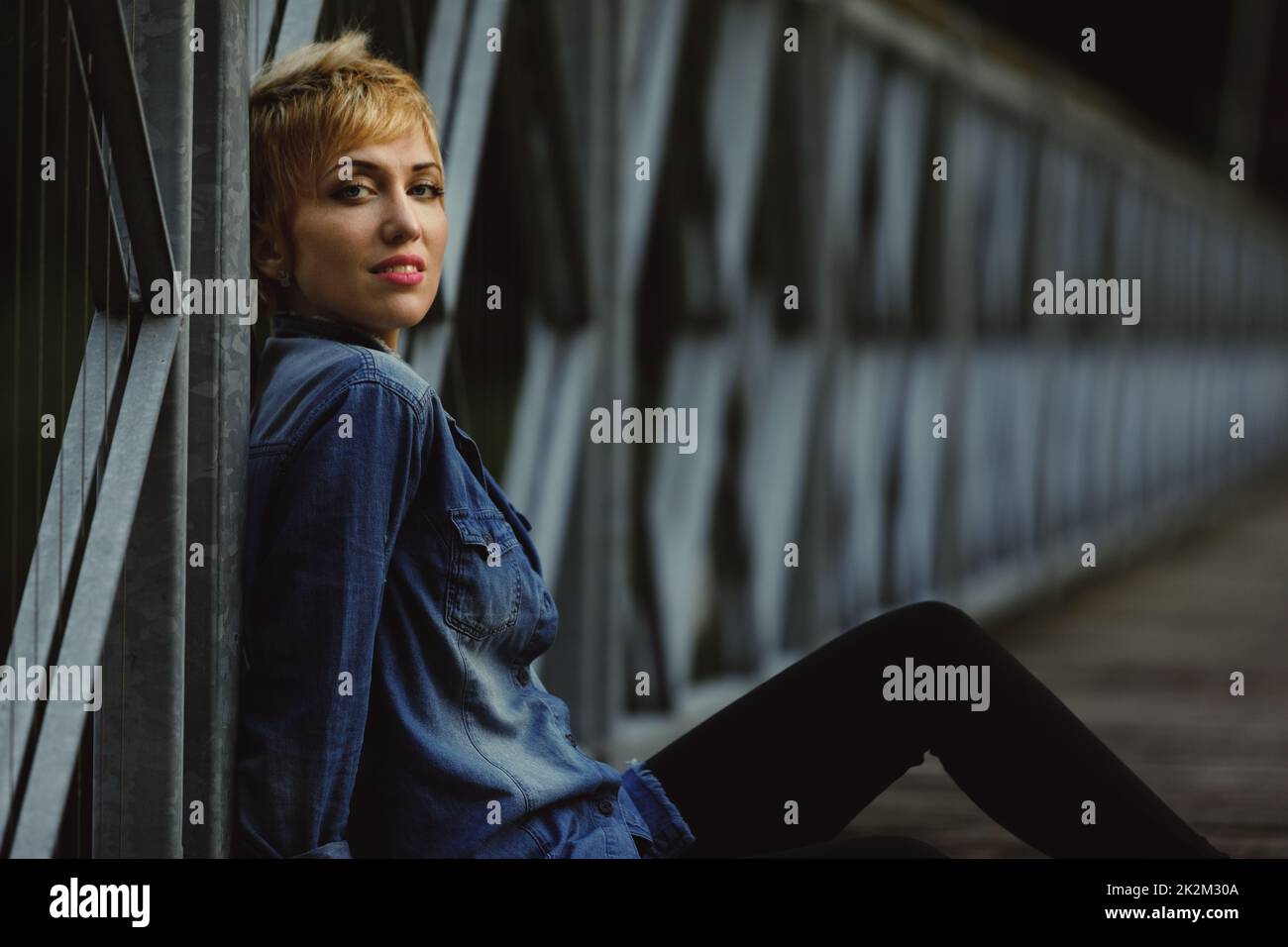 Donna solo attraente seduta su un vecchio ponte la sera Foto Stock