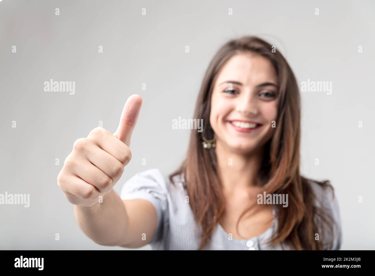 Sorridente donna attraente dando un pollice in alto Foto Stock