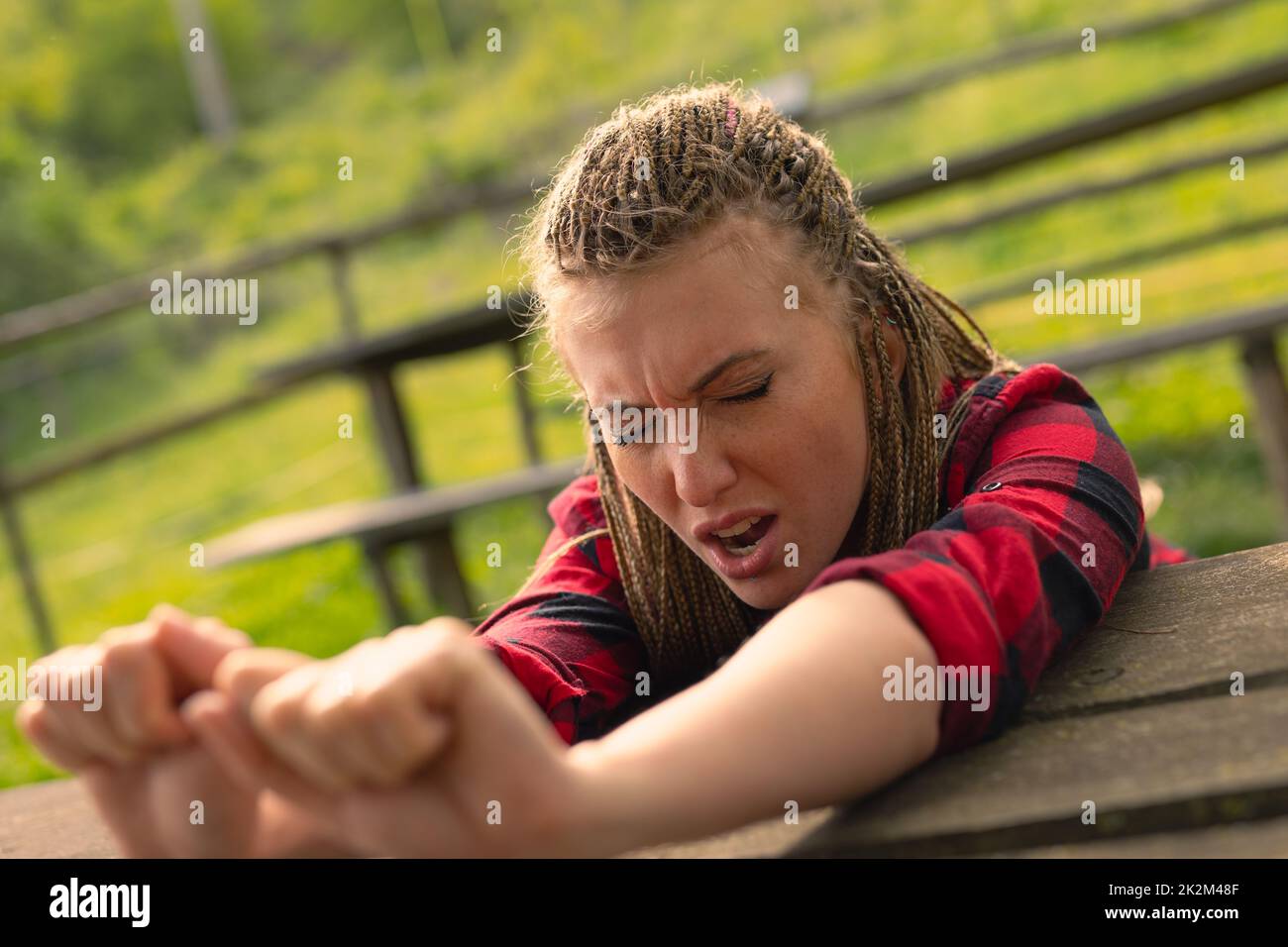 donna che allunga le braccia su un tavolo che sbadigna nel parco Foto Stock
