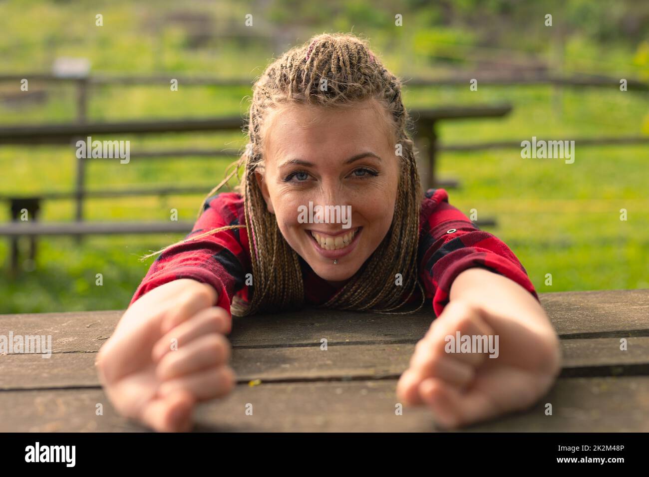 donna che allunga le braccia su un tavolo che sbadigna nel parco Foto Stock