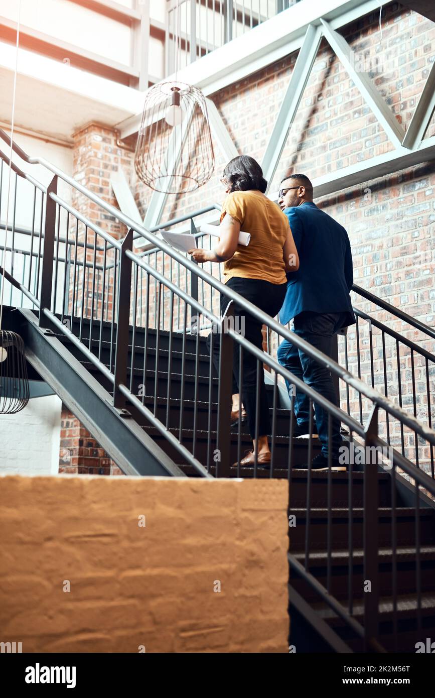 Portare la scala al successo. Foto di due designer che hanno una discussione su una scala in un ufficio. Foto Stock