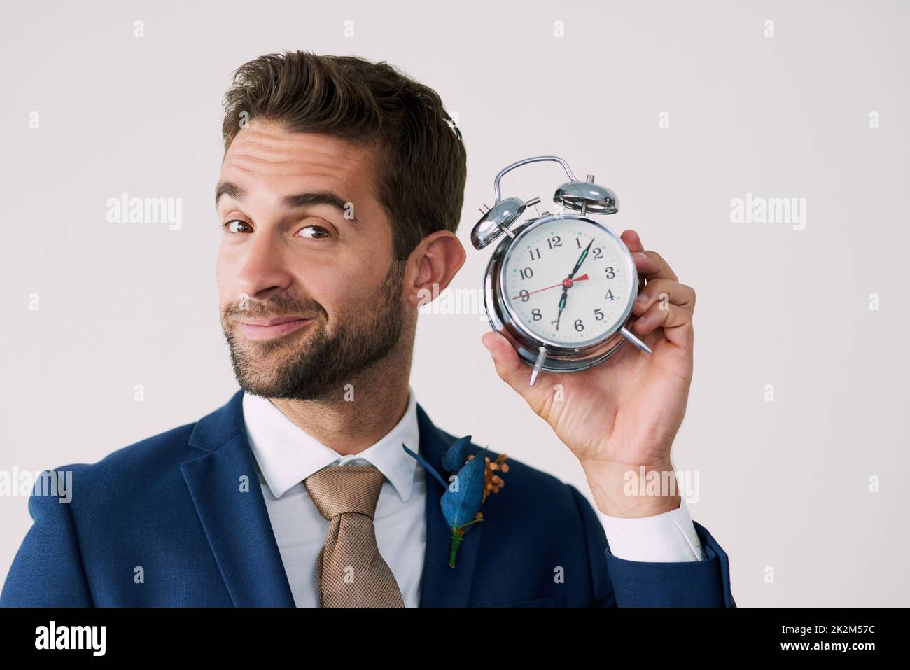 L'attesa è finita. Studio girato di un bel giovane sposo che tiene un orologio su uno sfondo grigio. Foto Stock