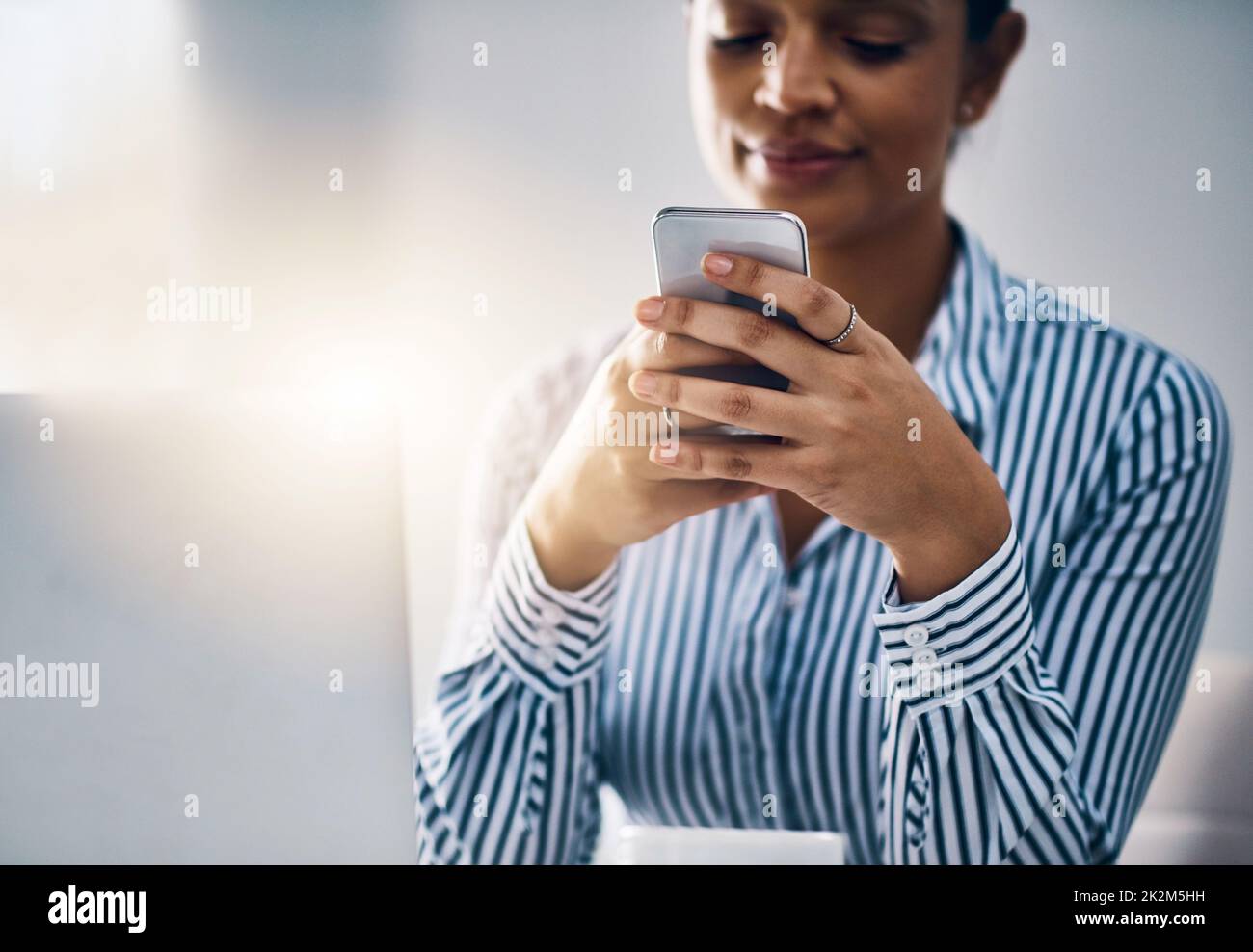 Far funzionare il software mobile per lei. Scatto di una giovane donna d'affari che usa un cellulare in un ufficio. Foto Stock
