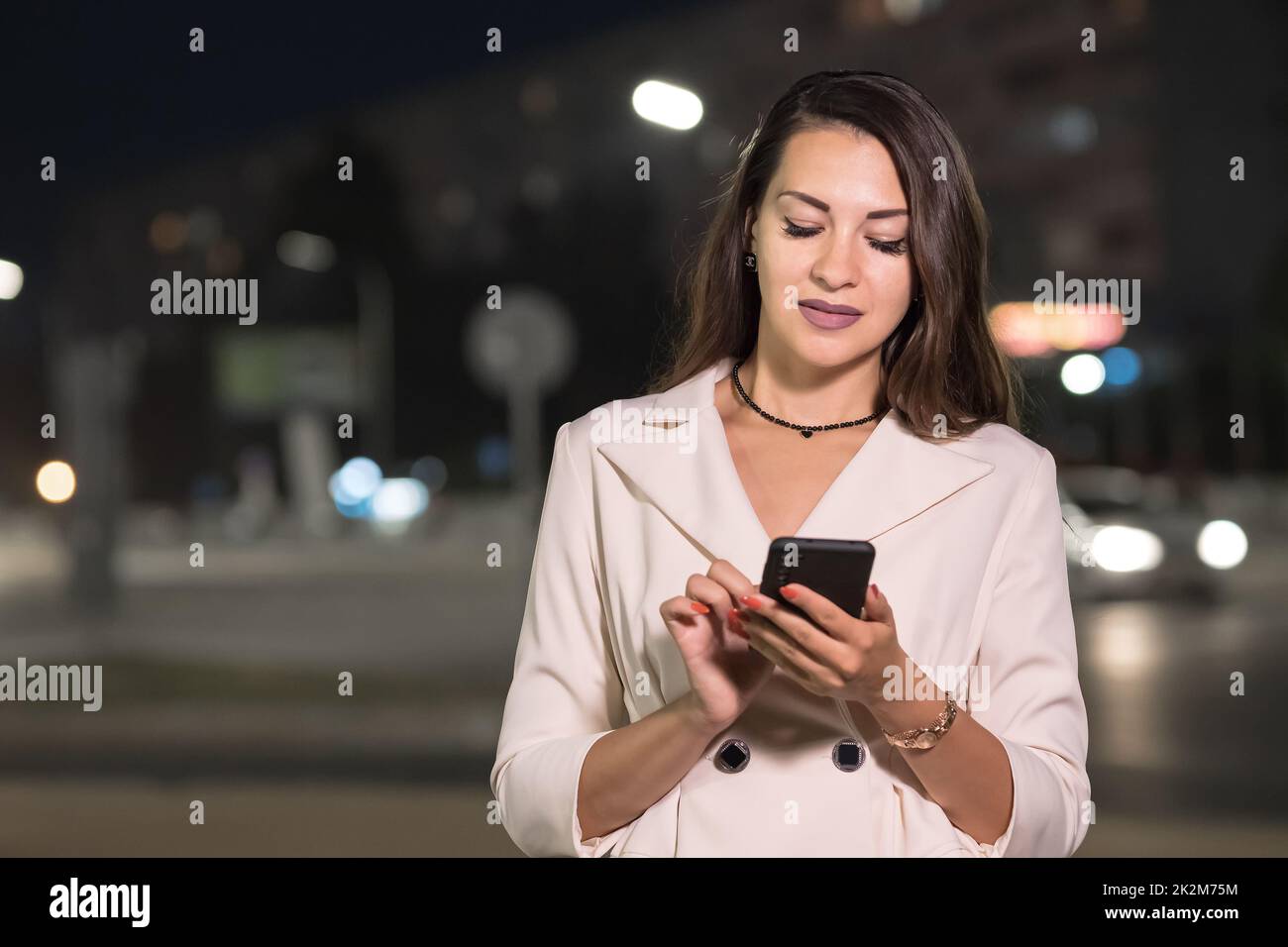 Una donna d'affari dai capelli lunghi digita i messaggi sullo smartphone Foto Stock