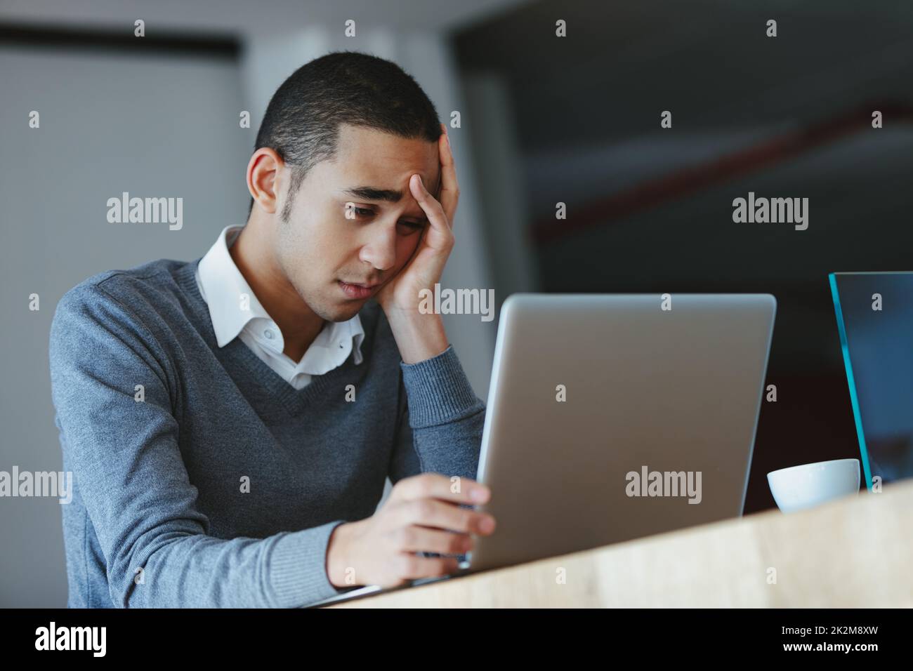 Annoiato o esausto uomo d'affari che fissava il suo laptop Foto Stock