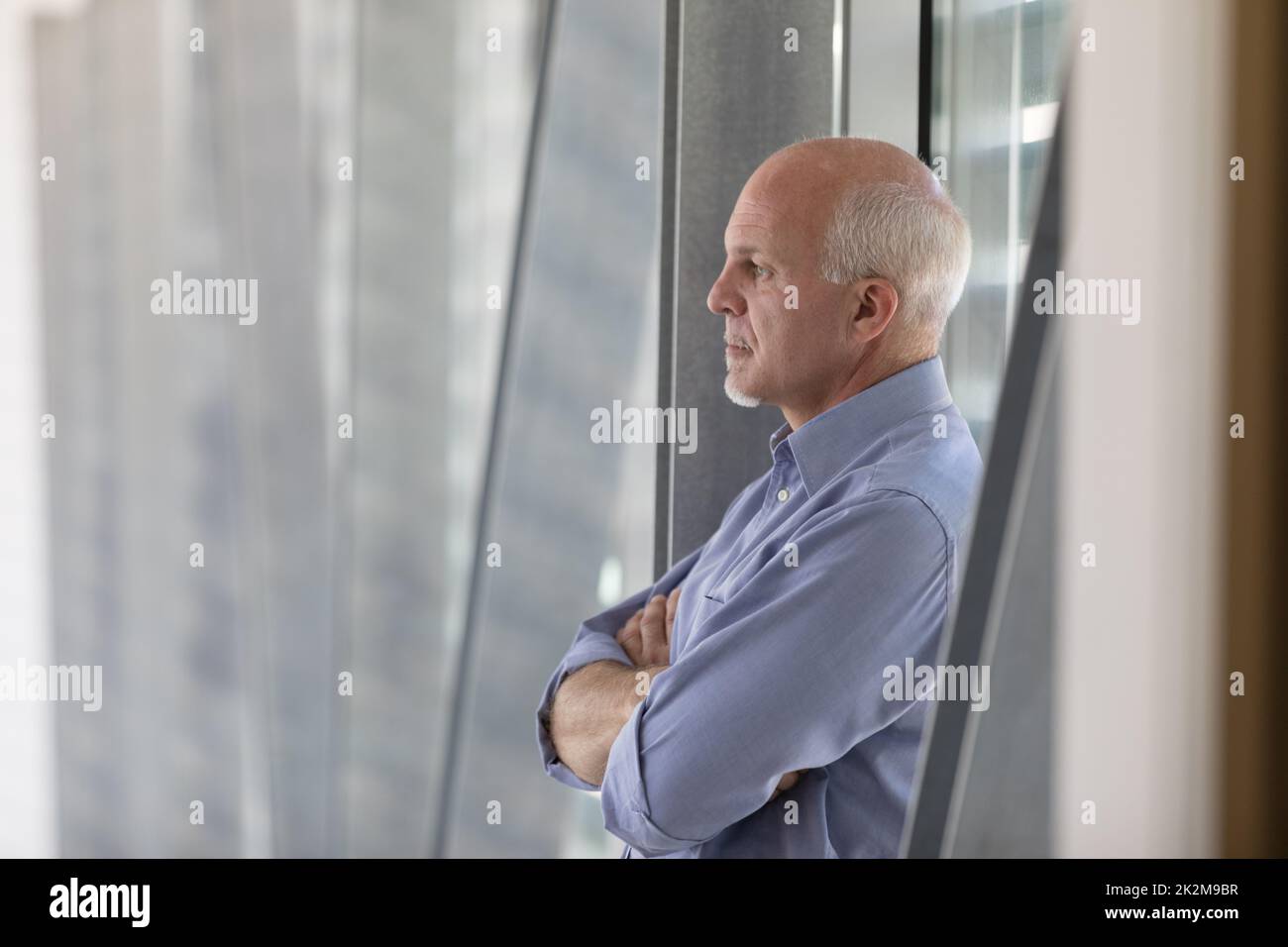 Uomo anziano dai capelli grigi in piedi nel profondo del pensiero Foto Stock