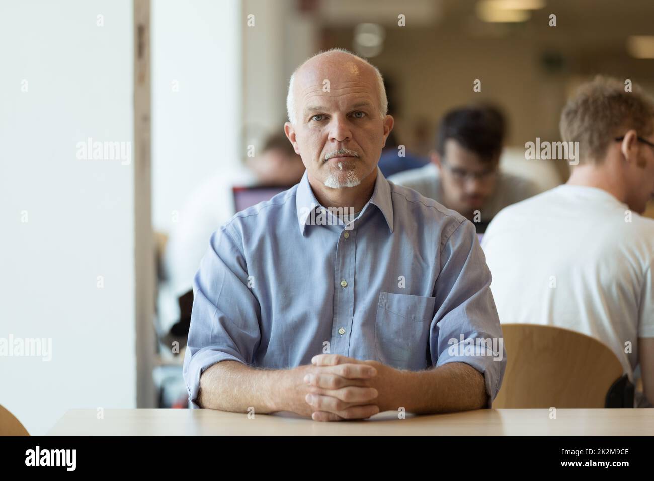 Serio uomo anziano seduto da solo in una caffetteria Foto Stock