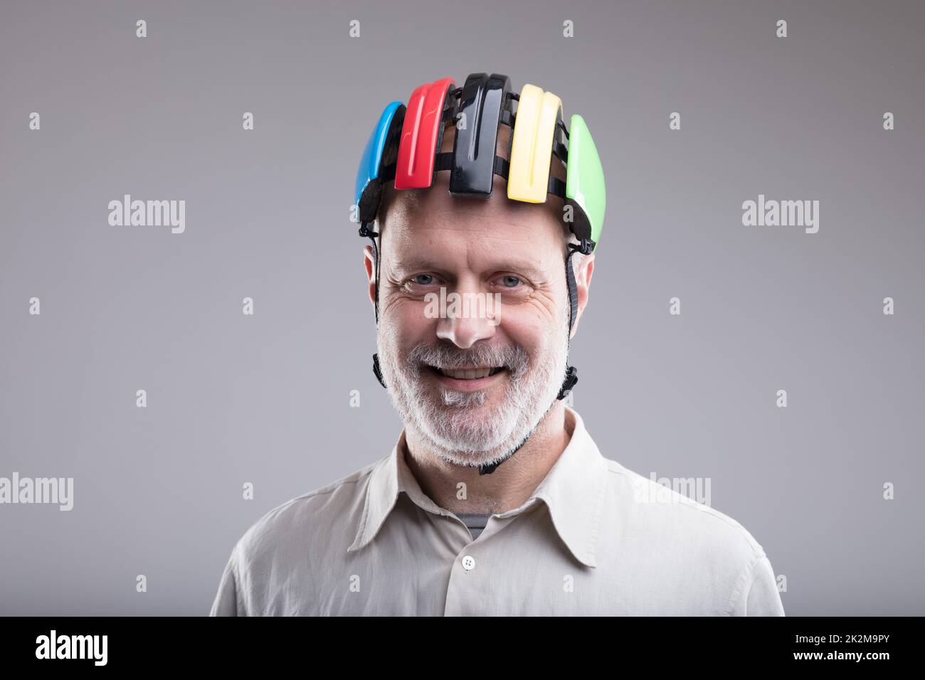 vecchio uomo sorridente che indossa un casco da bici Foto Stock