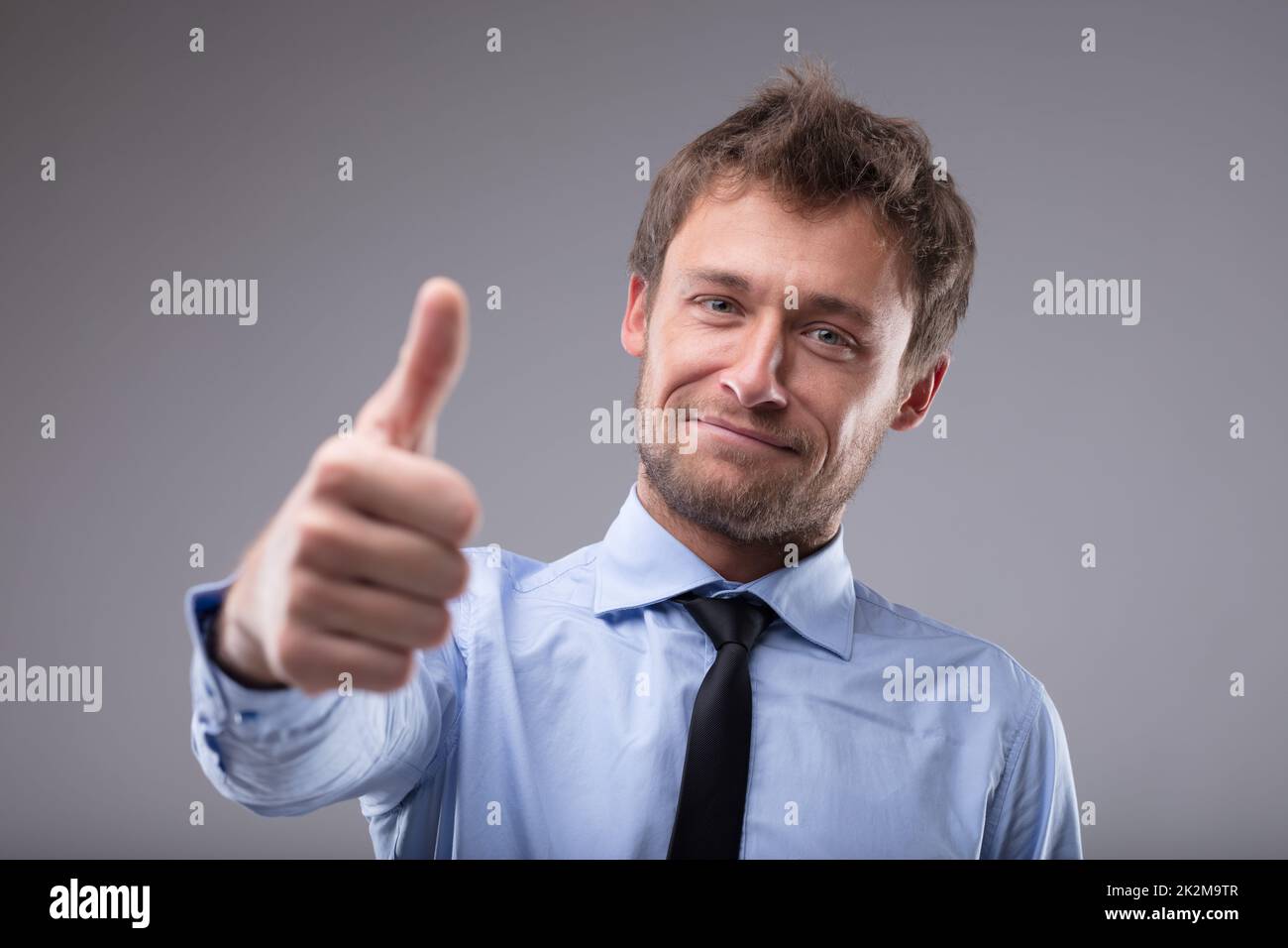 Felice uomo di successo che dà un pollice su gesto Foto Stock