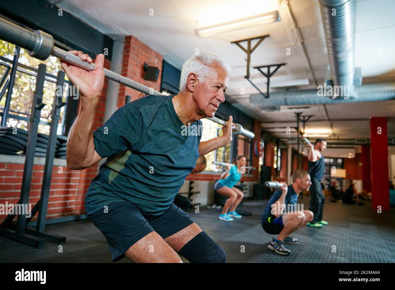 Il vero allenamento inizia quando vuoi fermarti. Scatto di un uomo anziano che si allenano in un centro benessere con la gente sfocata in background. Foto Stock