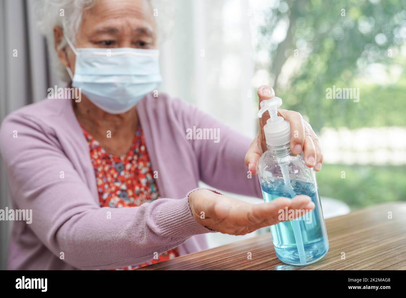 Paziente anziana asiatica che indossa una maschera protettiva per proteggere l'ambiente inquinante e il coronavirus COVID-19. Foto Stock