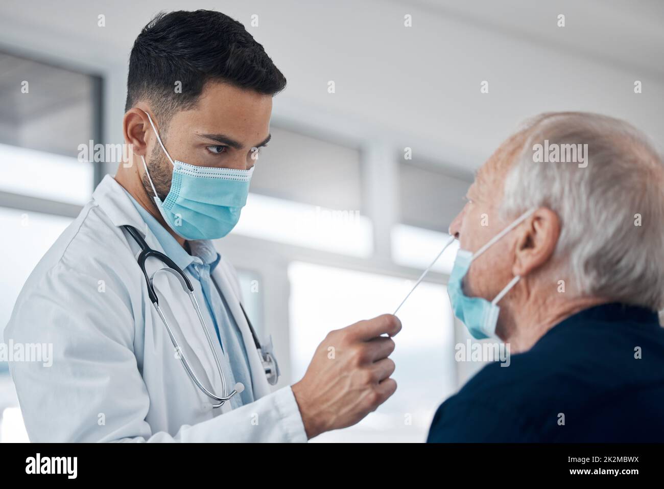 Persone positive che hanno diritto al vaccino. Scatto corto di un bel medico giovane maschio che esamina un paziente anziano per il covid. Foto Stock