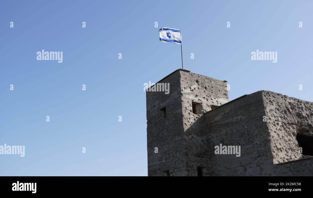 Le rovine della British mandate Police Station a Ein Tina all'inizio della riserva naturale del torrente Amud, alta Galilea, Israele settentrionale. Edificio storico in cemento con la bandiera israeliana in cima Foto Stock