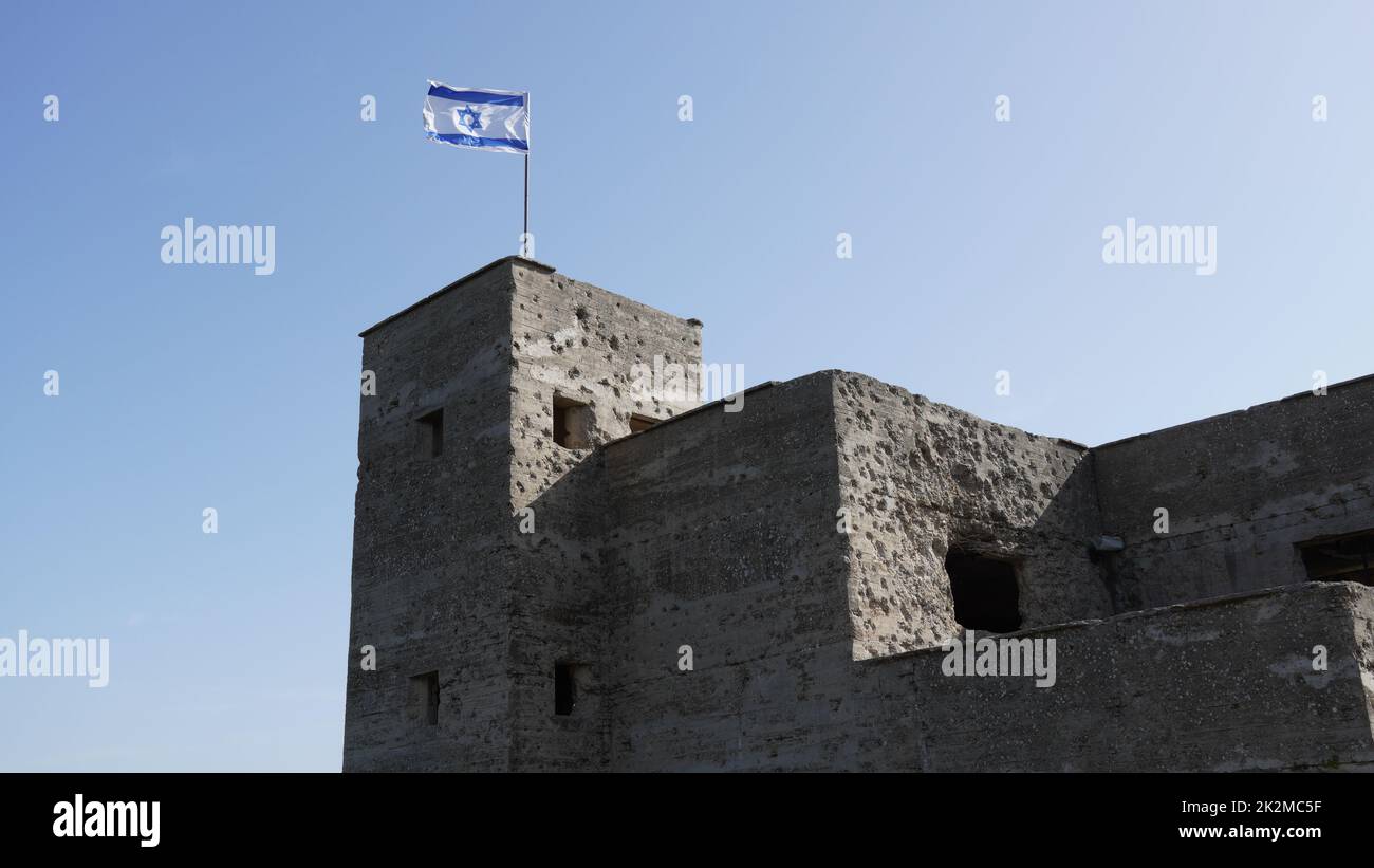 Le rovine della British mandate Police Station a Ein Tina all'inizio della riserva naturale del torrente Amud, alta Galilea, Israele settentrionale. Edificio storico in cemento con la bandiera israeliana in cima Foto Stock