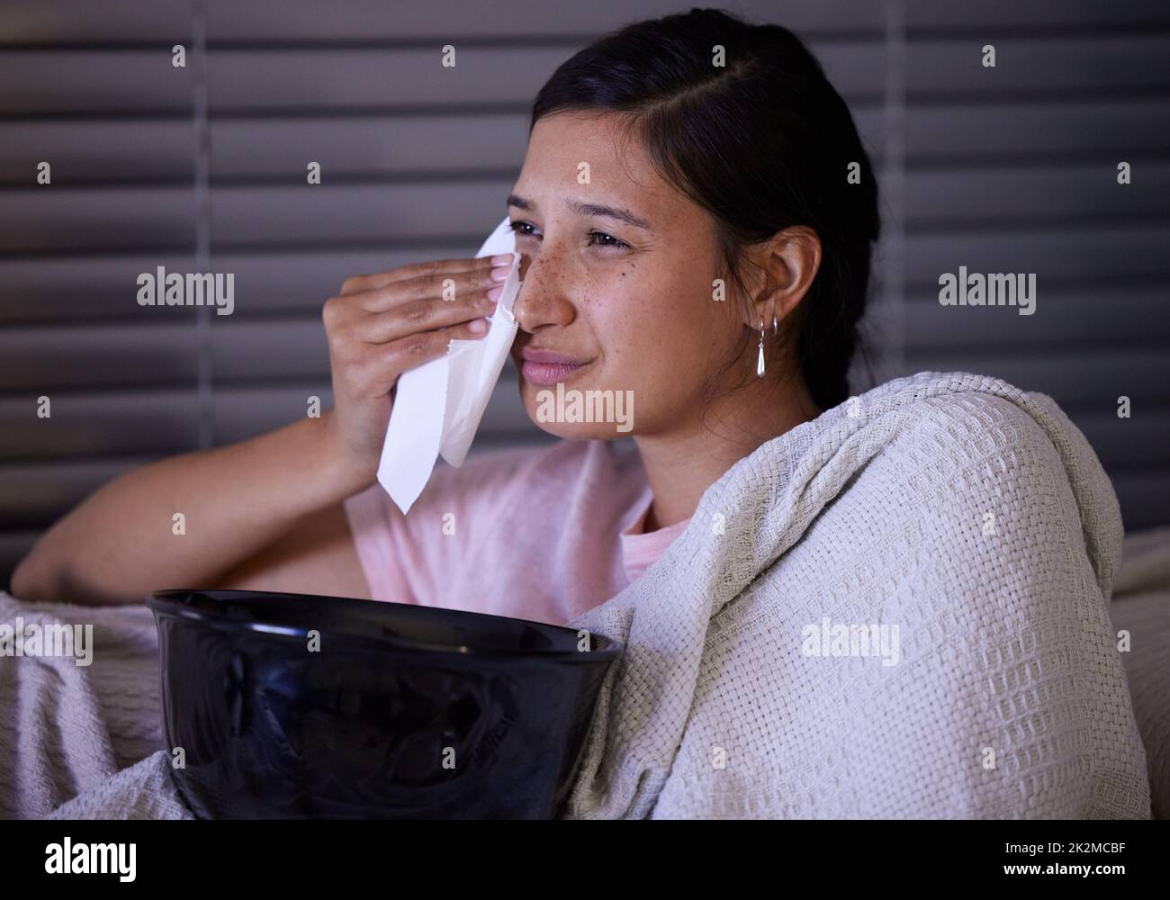 A volte tutto quello di cui avete bisogno è un buon film a cui piangere. Scatto di una giovane donna che piange mentre guarda la tv a casa. Foto Stock