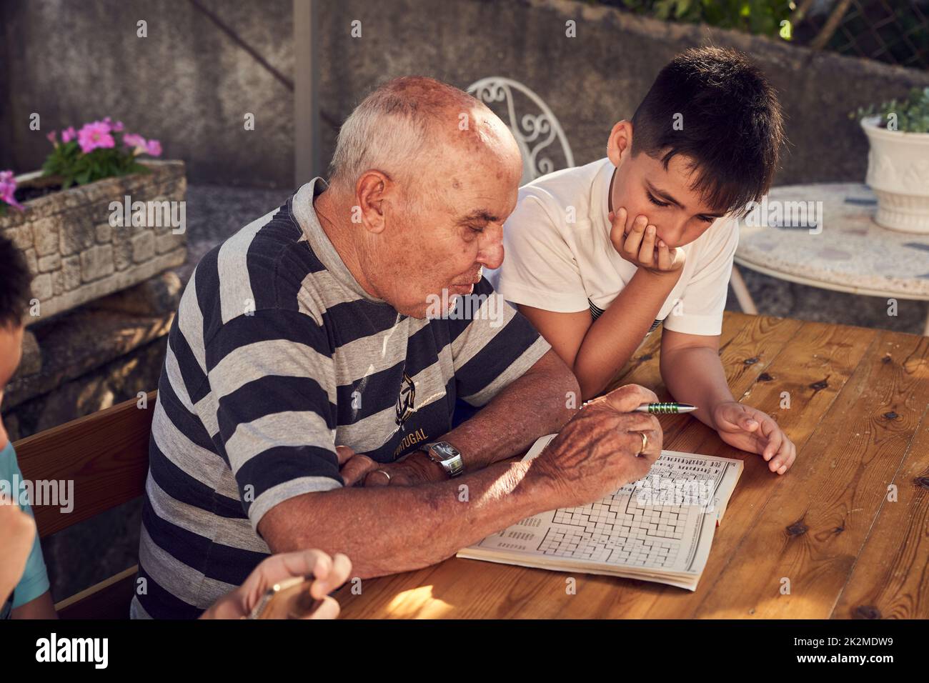 Un uomo anziano seduto a fare hobby a parole incrociate con suo nipote. Foto Stock