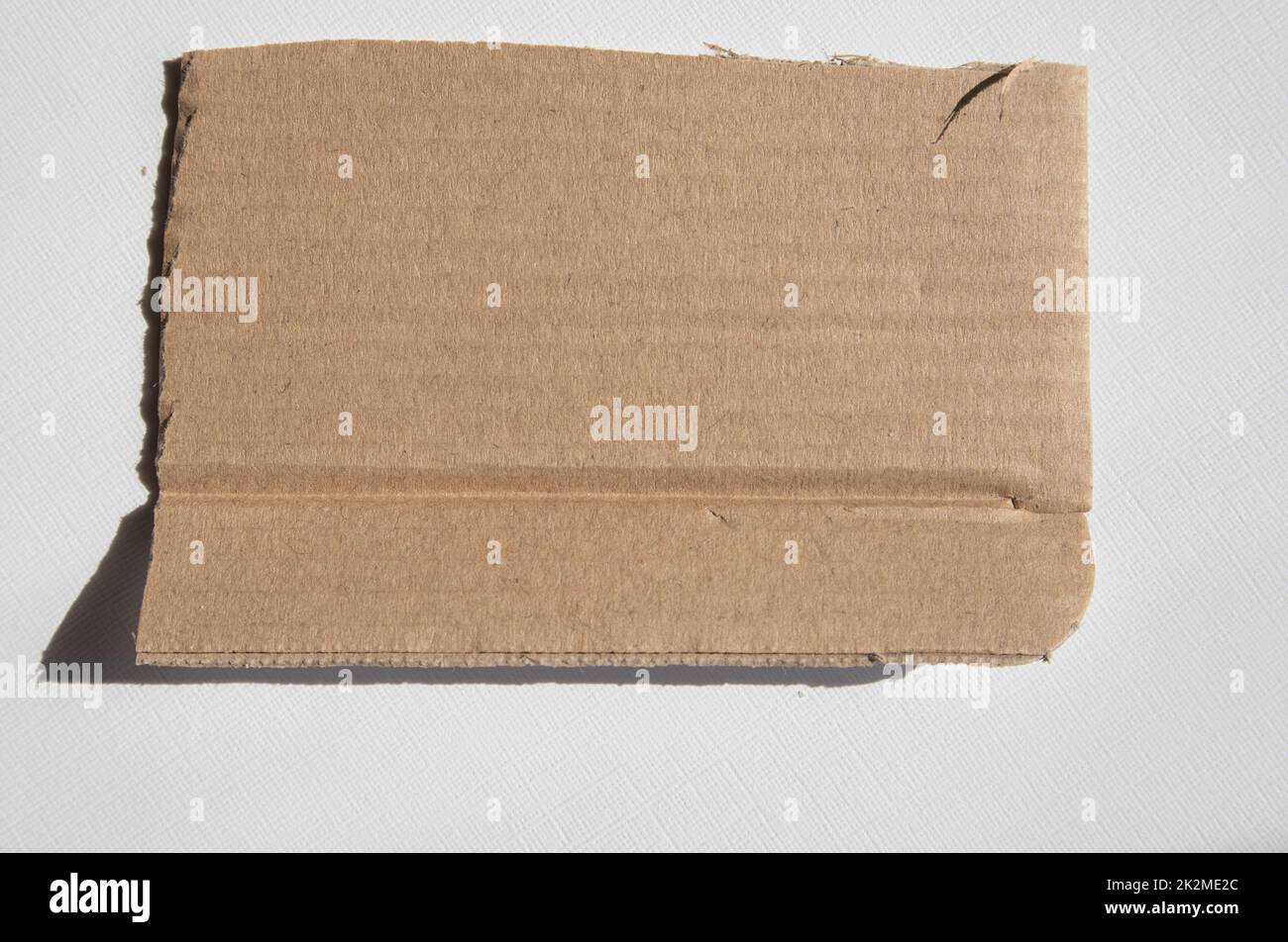 Un pezzo strappato di cartone kraft su sfondo bianco. Modello, posizione per il testo Foto Stock