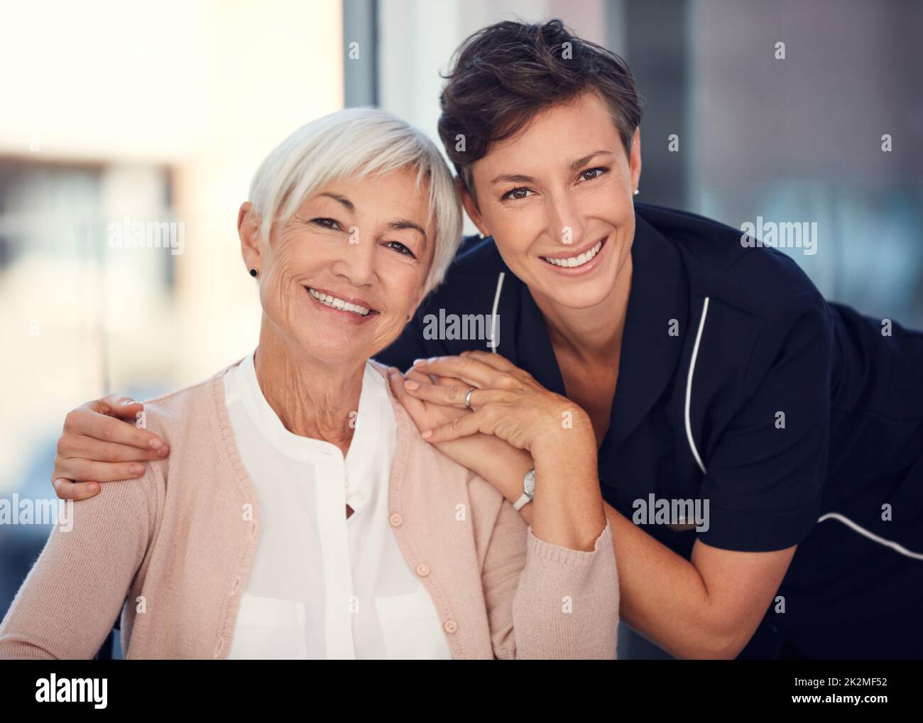 Ho un pilastro di forza in lei. Ritratto corto di una giovane infermiera che abbraccia una donna anziana seduta in una sedia a rotelle in una casa di cura. Foto Stock