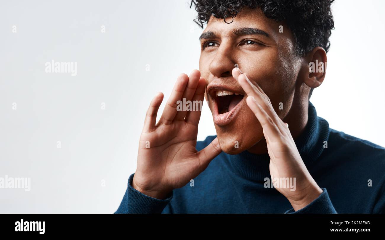 Le notizie viaggiano più velocemente per bocca che per posta. Studio girato di un giovane uomo urlando su uno sfondo grigio. Foto Stock