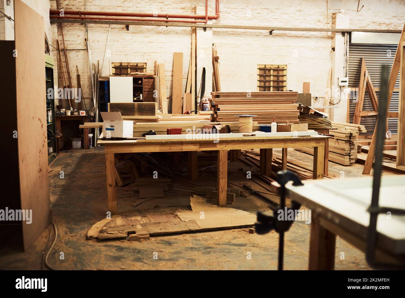 Qui accade tutta la magia. Foto di vita di tavoli da lavoro e mucchi di legno all'interno di un'officina di carpenteria. Foto Stock