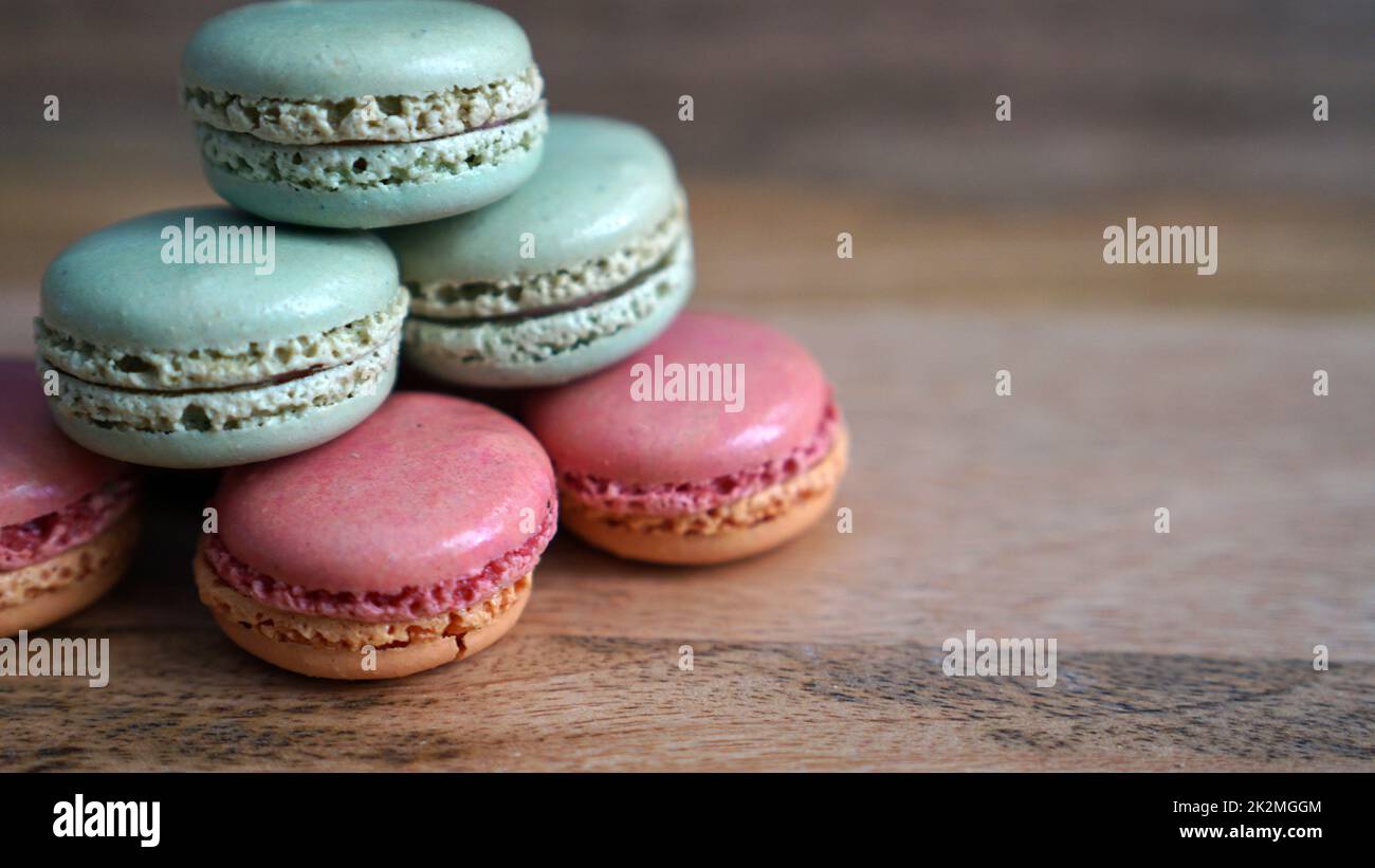 Macaron verdi e rosa impilati su uno sfondo di legno Foto Stock