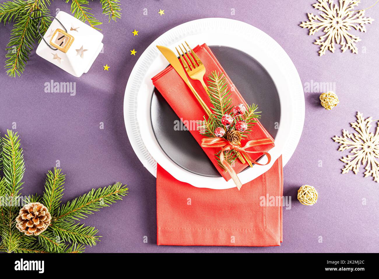 Bel design moderno del servizio natalizio del tavolo festivo. Tovaglioli rossi piegati in un ventilatore con decorazioni su piatti bianchi e scuri Foto Stock