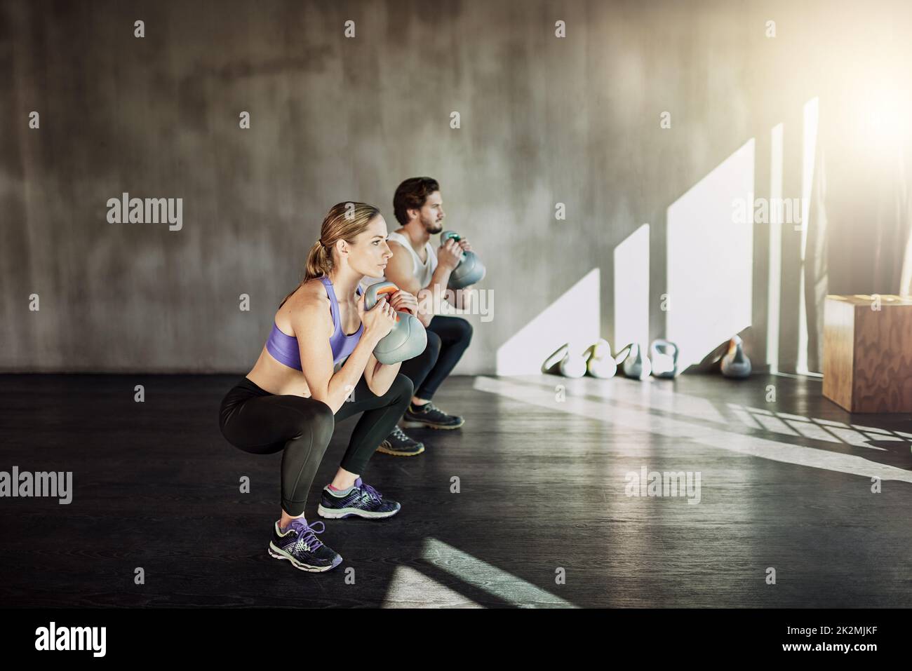 Allenamento come la tua vita dipende da esso. Shot di due giovani che si allenano in palestra utilizzando le campane del bollitore. Foto Stock