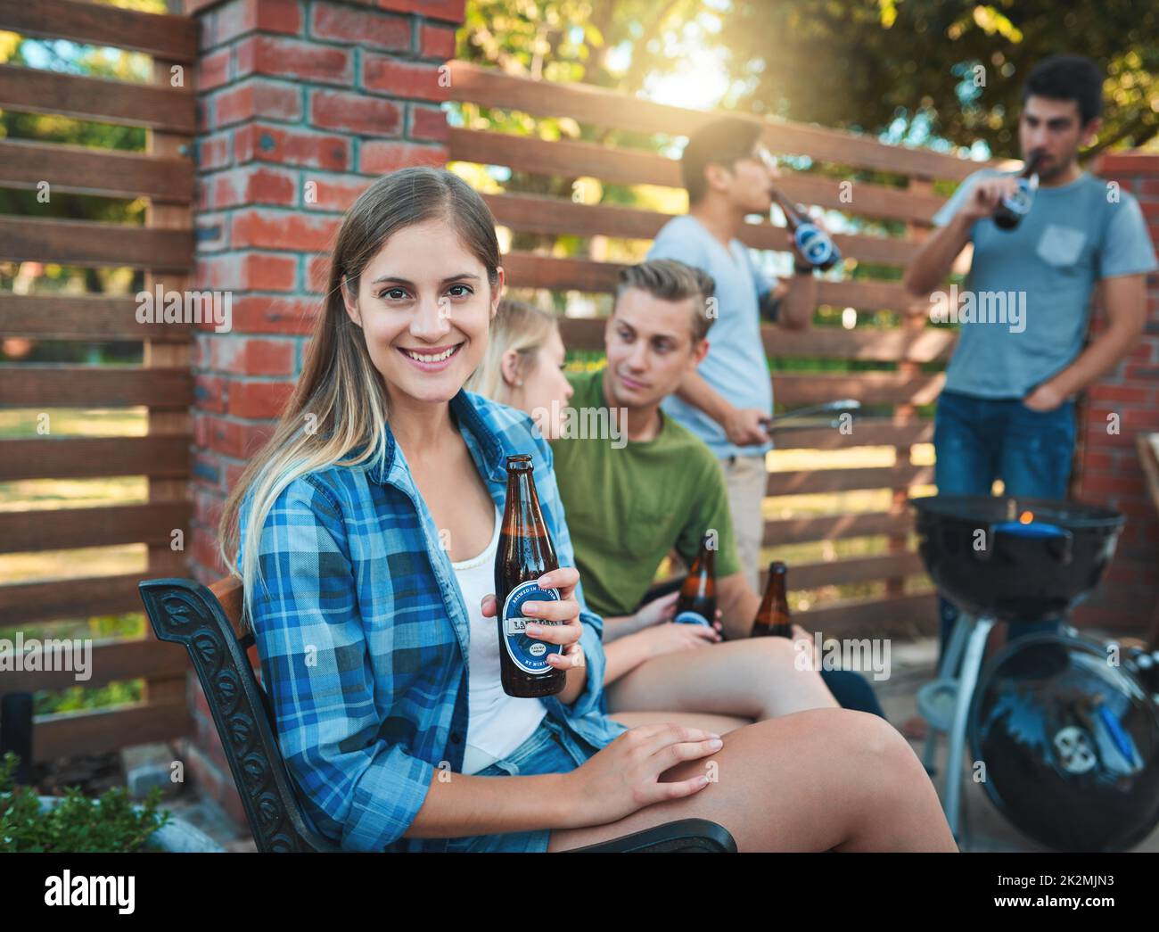 Un altro fine settimana, un altro chill sesh. Scatto di una giovane donna felice godendo una birra ad un barbecue con i suoi amici. Foto Stock
