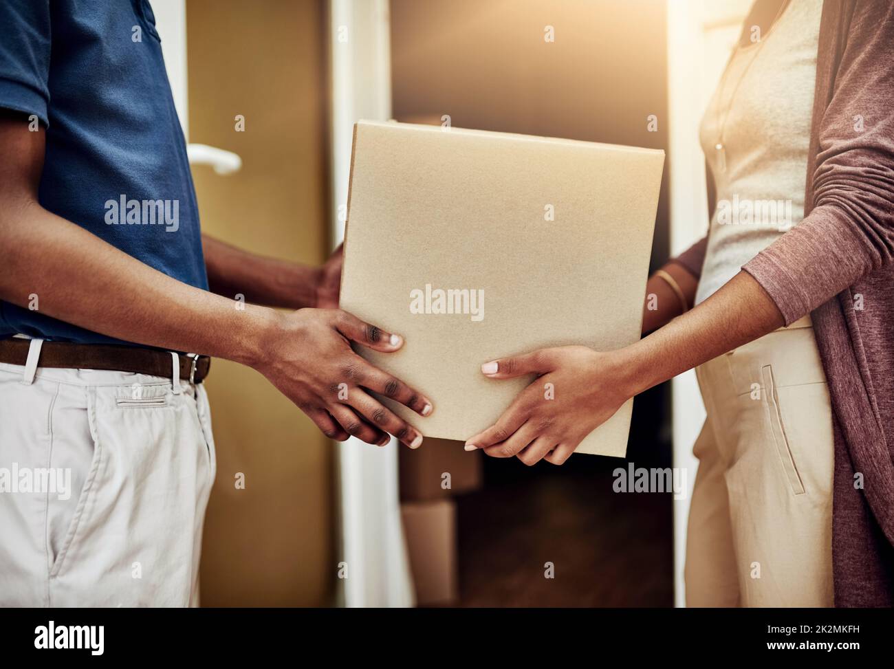 Dalle nostre mani alle tue. Scatto di un impiegato postale che consegna un pacchetto a una cliente femminile irriconoscibile. Foto Stock