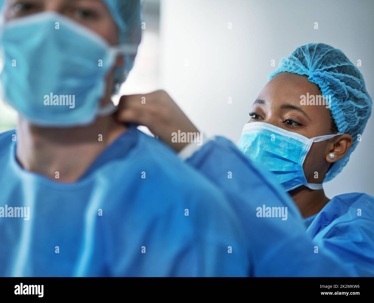 La sicurezza è fondamentale in ogni procedura medica. Shot di chirurghi che mettono su indumenti protettivi in preparazione per un intervento chirurgico. Foto Stock