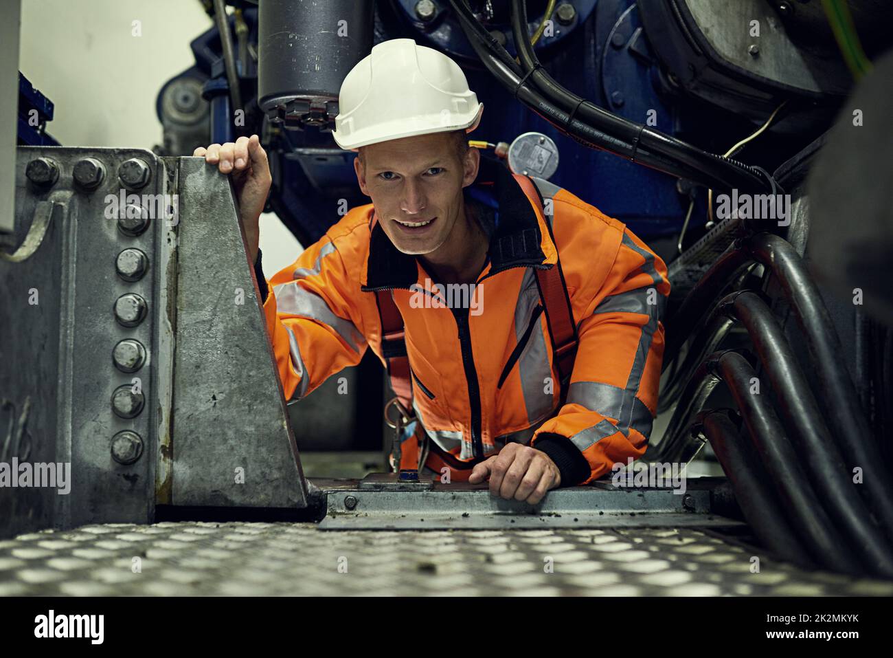 In questo lavoro, ci si abitua a piccoli spazi. Ritratto di un giovane ingegnere al lavoro indossando l'attrezzatura di sicurezza. Foto Stock
