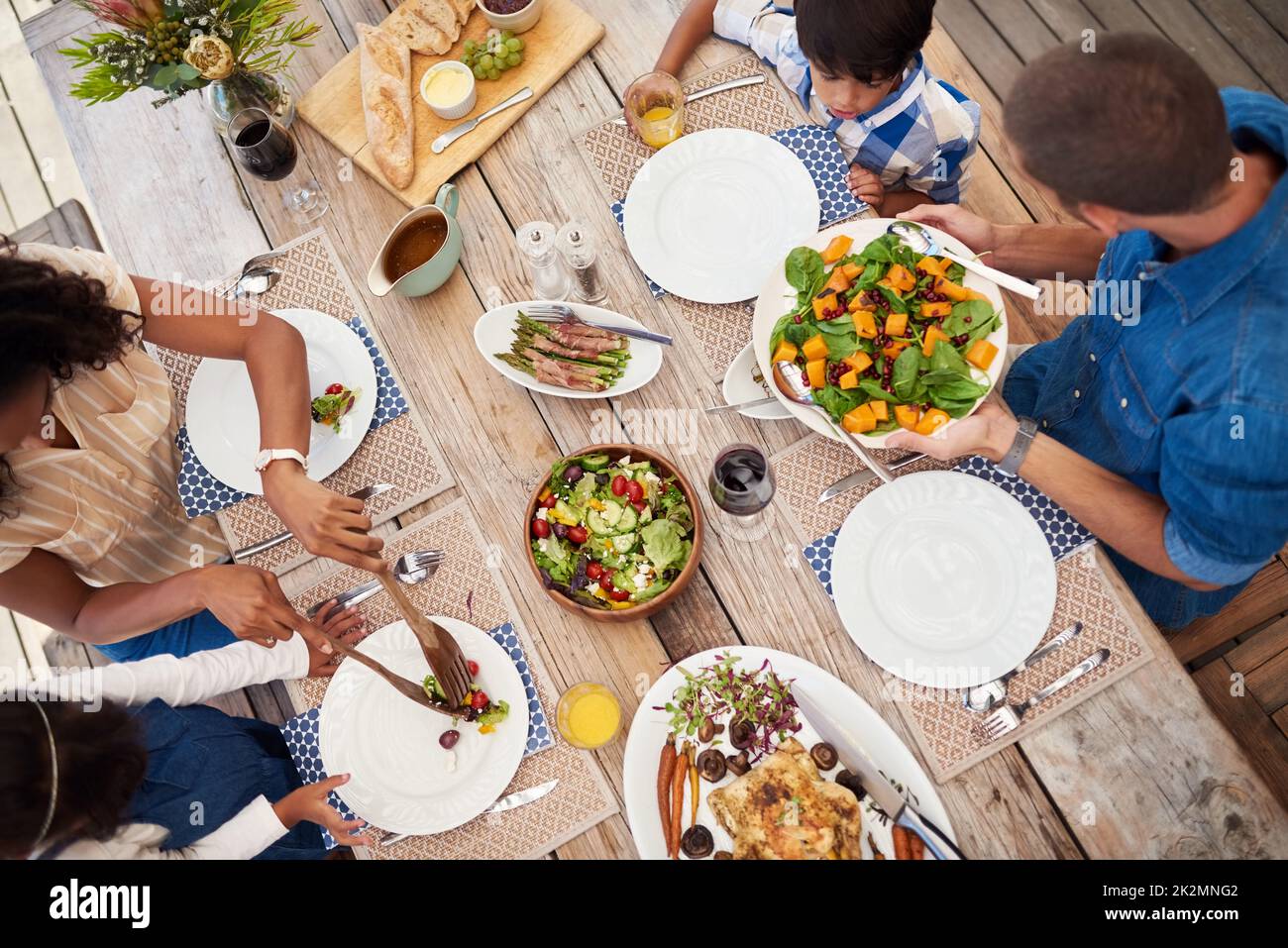 Servire l'amore e la felicità con ogni pasto. Inquadratura ad angolo di una giovane famiglia di quattro persone che gusta un pasto insieme intorno a un tavolo all'aperto. Foto Stock