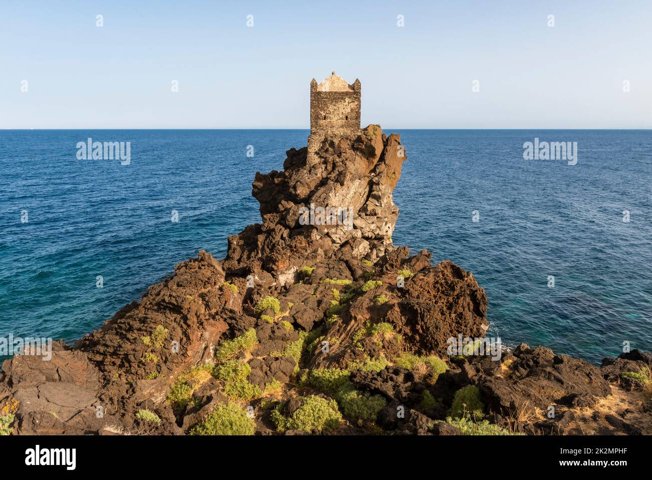 Una torre di guardia medievale arroccata su un affioramento di lava vulcanica che domina il Mar Ionio, vicino al piccolo villaggio di Santa Tecla, Acireale, Sicilia Foto Stock