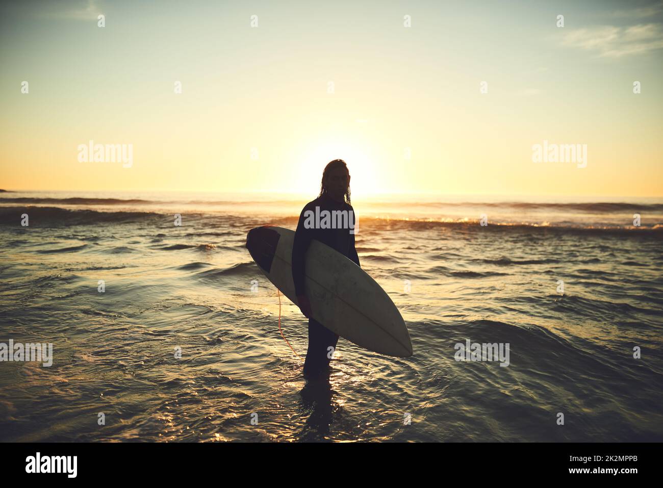 Dobbiamo raccogliere i benefici di tutto questo mare vitaminico. Scatto di un giovane che porta una tavola da surf in spiaggia. Foto Stock