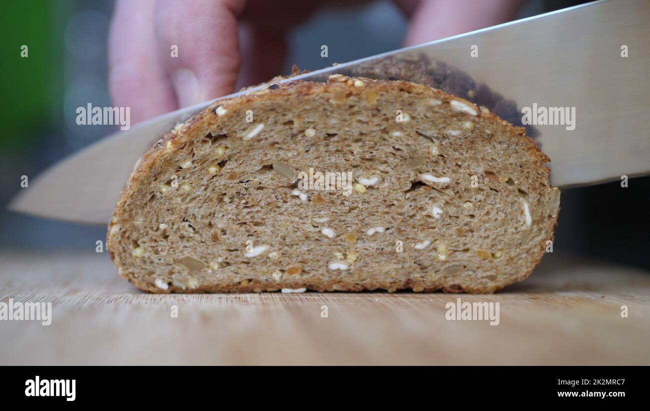 Affettare pane integrale su tavola di legno. Foto Stock