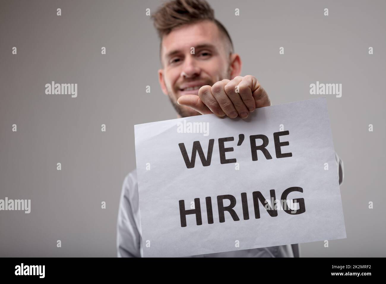 Uomo sorridente che tiene un segno We're Hiring Foto Stock